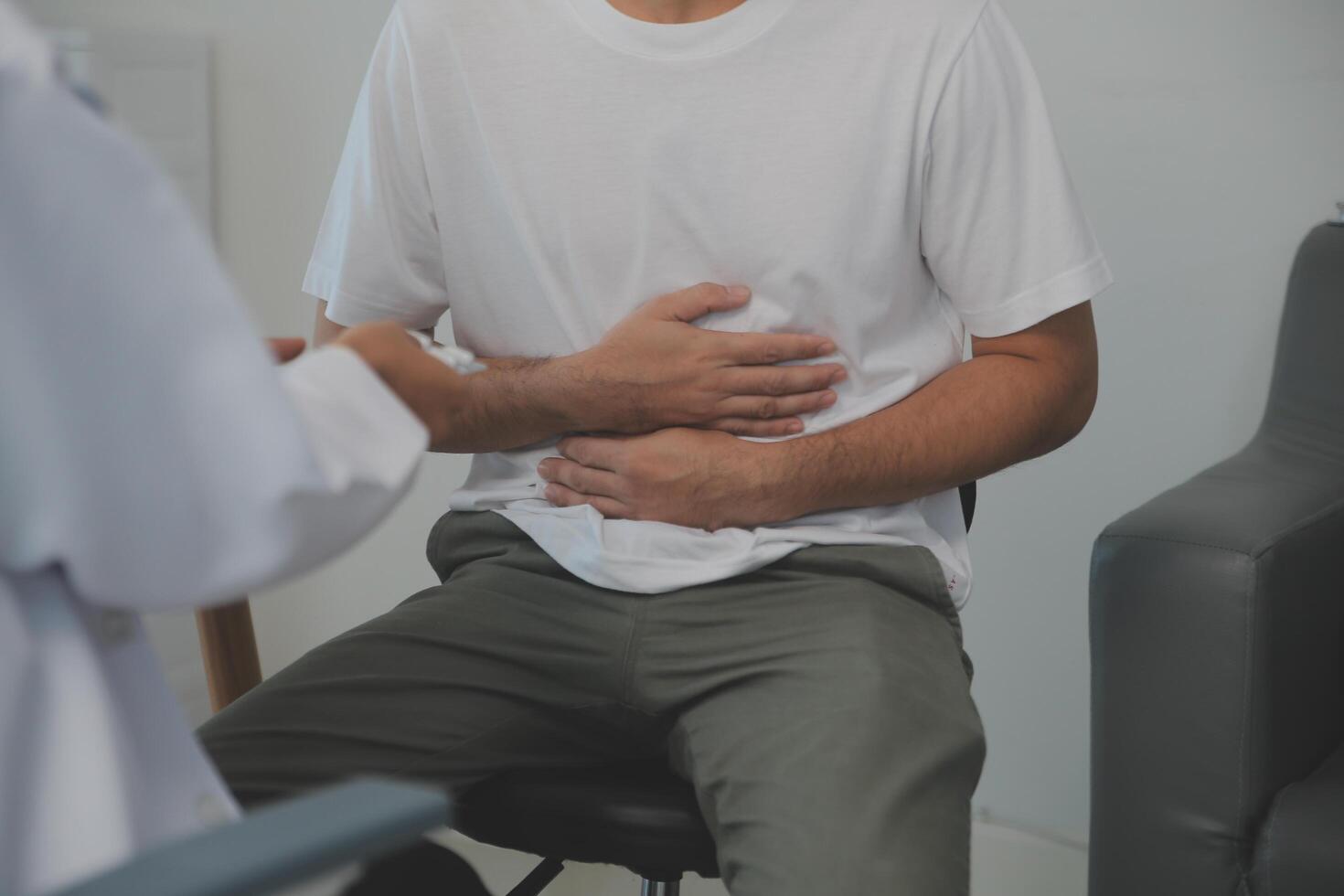 Man suffering with severe stomach pain sitting at home. Hand of mature guy holding abdomen suffering from ache, diarrhea or indigestive problem. Caucasian guy pressing on belly on painful sensation photo
