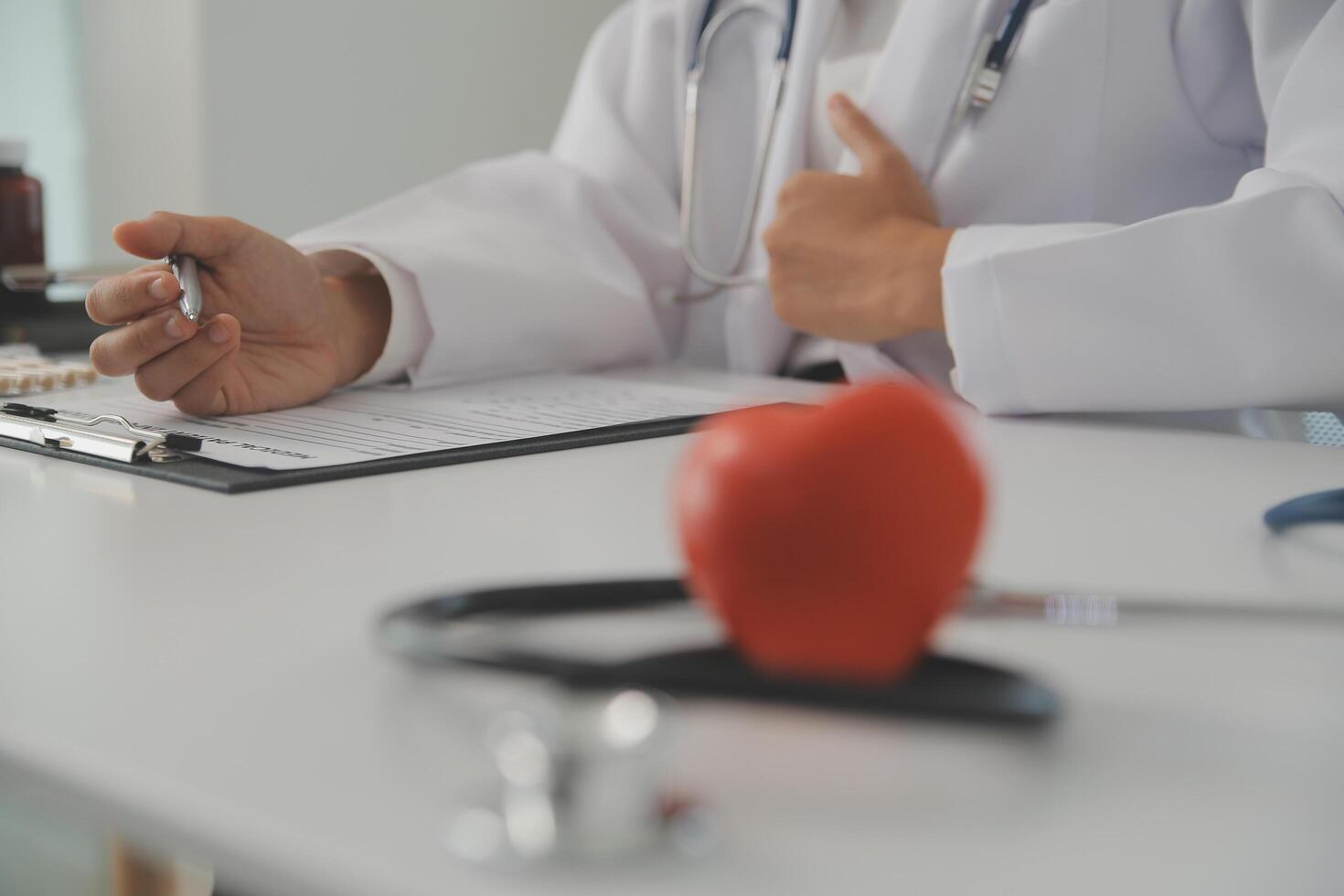 Hands of doctor woman holding red heart, showing symbol of love, human support to patient, promoting medical insurance, early checkup for healthcare, cardiologist help. Close up of object photo