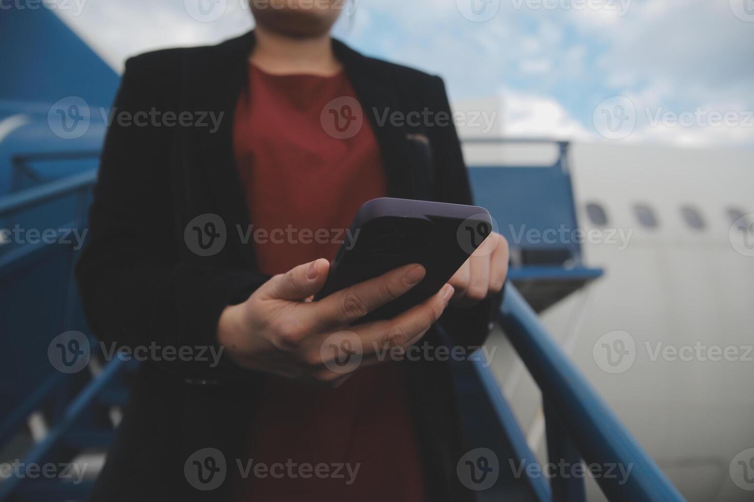 Young asian woman in international airport, using mobile smartphone and checking flight at the flight information board photo