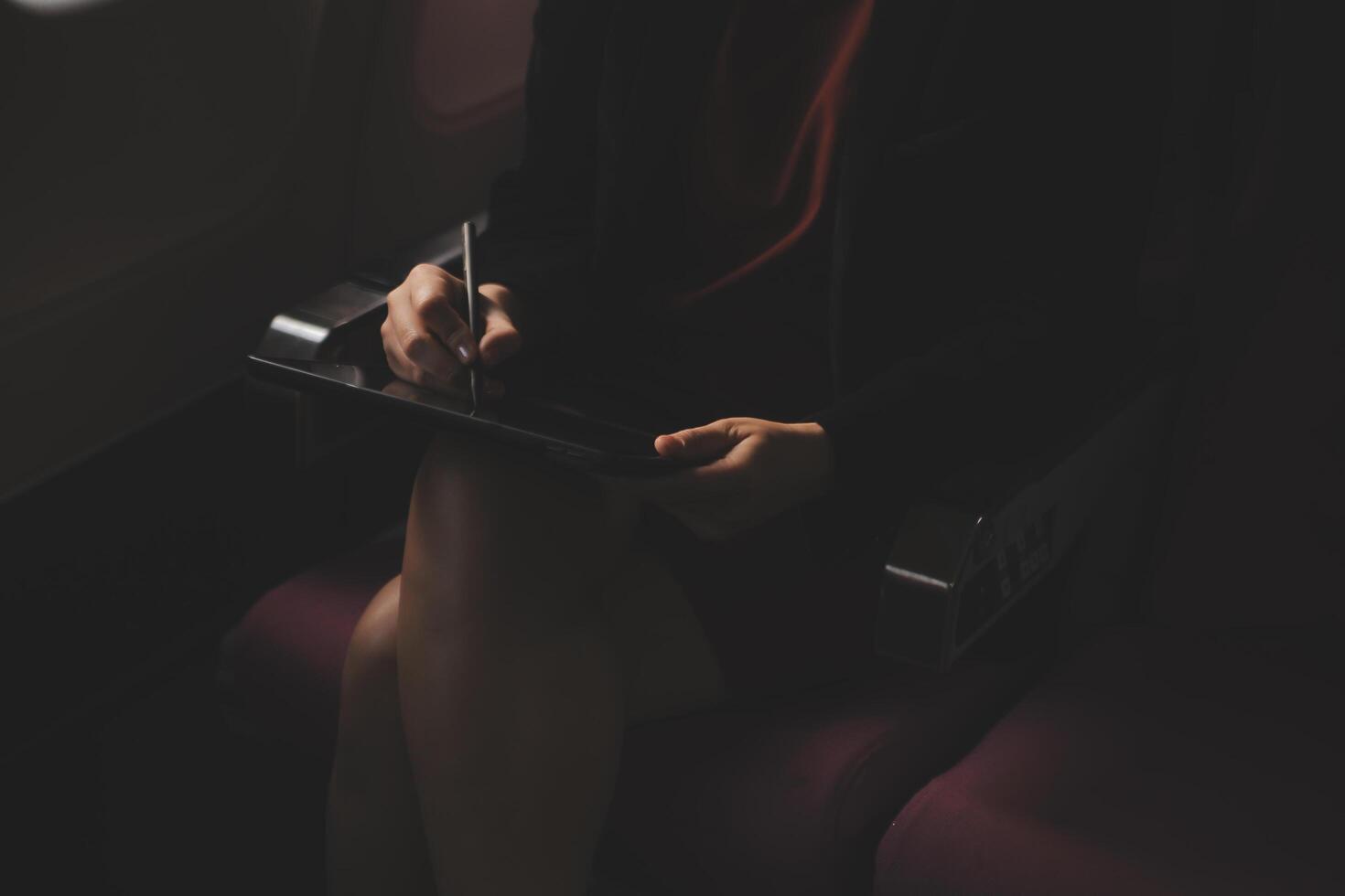 Blonde female tourist checking incoming notification on smartphone sitting on seat of airplane with netbook.Young businesswoman share media from telephone on laptop computer during plane flight photo