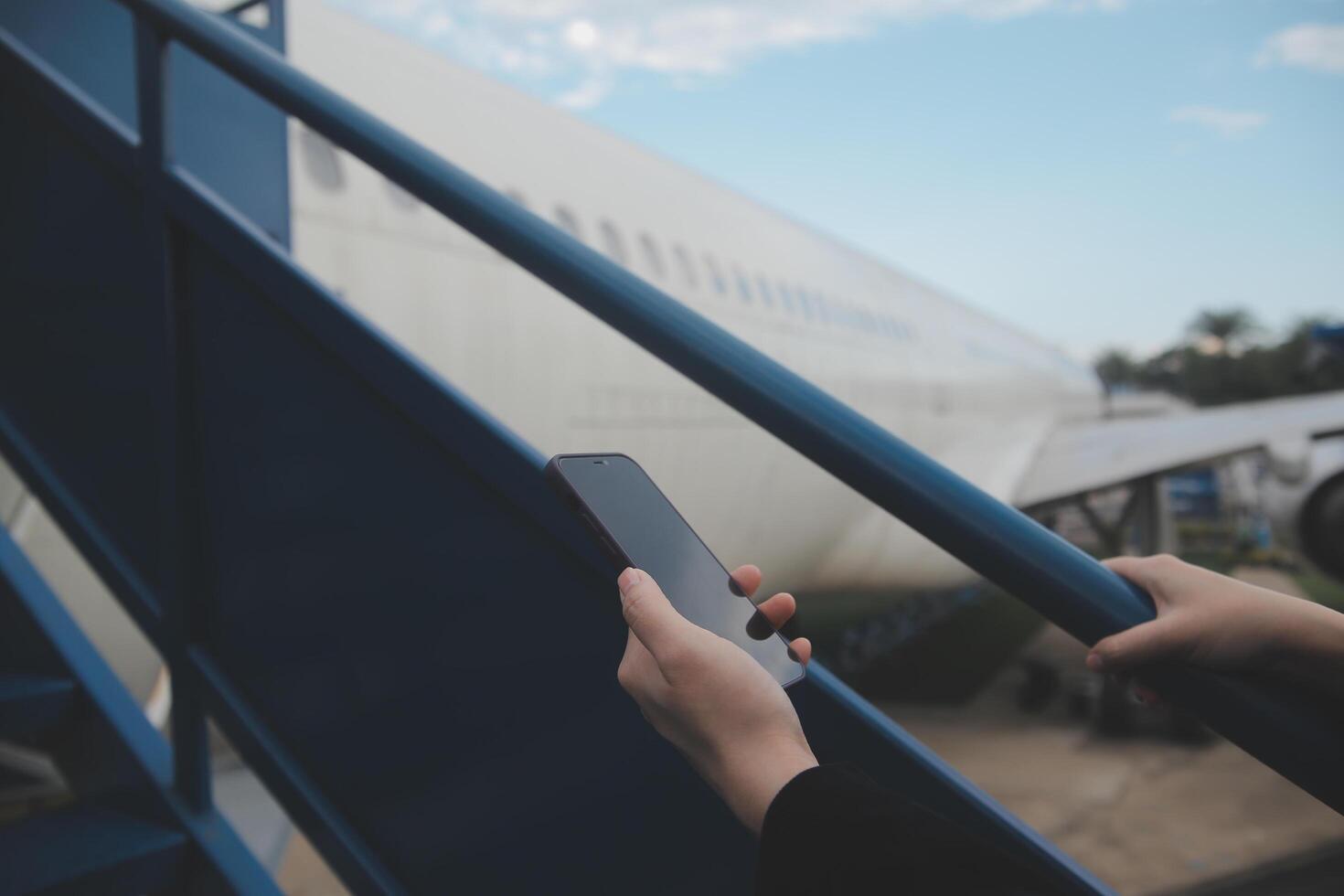 Young asian woman in international airport, using mobile smartphone and checking flight at the flight information board photo