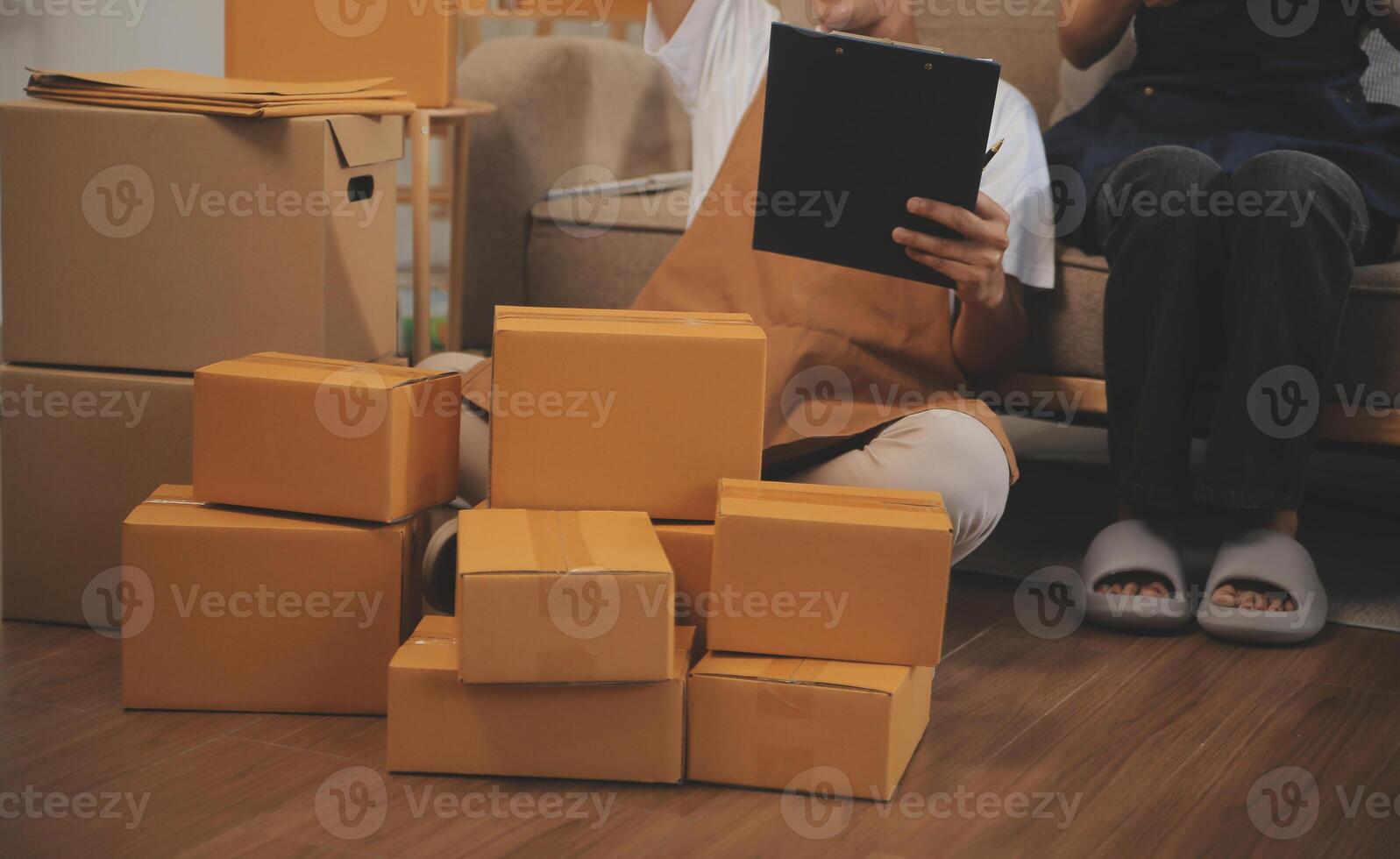 Two Asian blogger showing clothes in front of the camera to recording vlog video live streaming at her shop. Online Shopping Cart notion. on sofa at home photo
