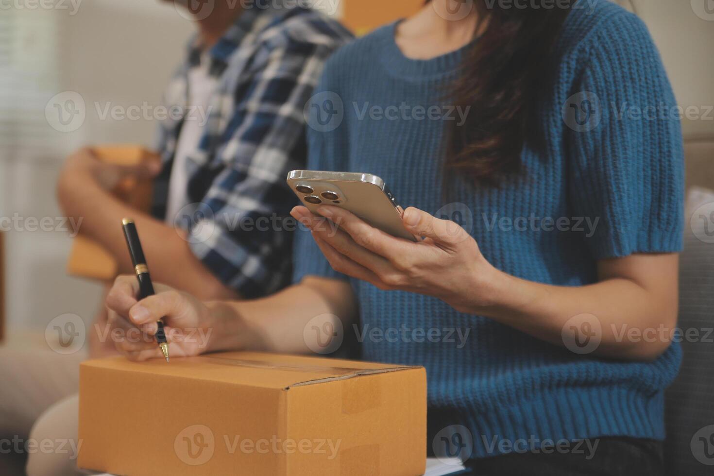 Two Asian blogger showing clothes in front of the camera to recording vlog video live streaming at her shop. Online Shopping Cart notion. on sofa at home photo