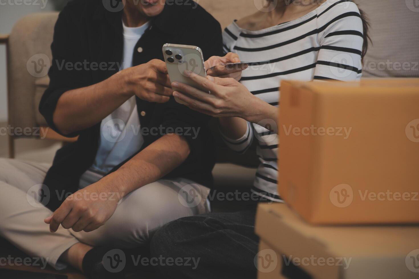 Two Asian blogger showing clothes in front of the camera to recording vlog video live streaming at her shop. Online Shopping Cart notion. on sofa at home photo