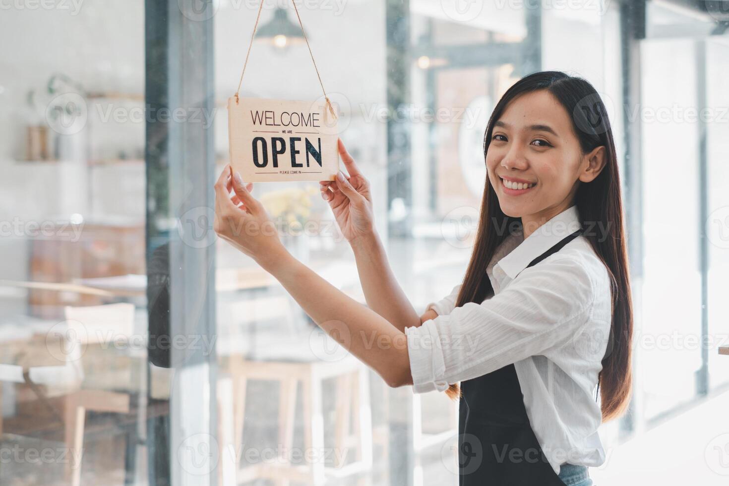 A dedicated cafe owner hangs an inviting Welcome Open sign, signaling the start of the day in her cozy coffee shop, an emblem of small business hospitality and readiness. photo