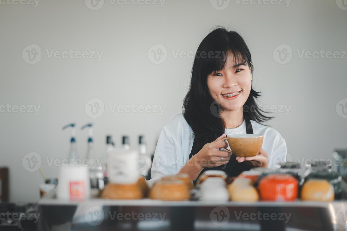 Smilling Beautiful woman barista hand holding cup of coffee for customer in coffee shop. photo