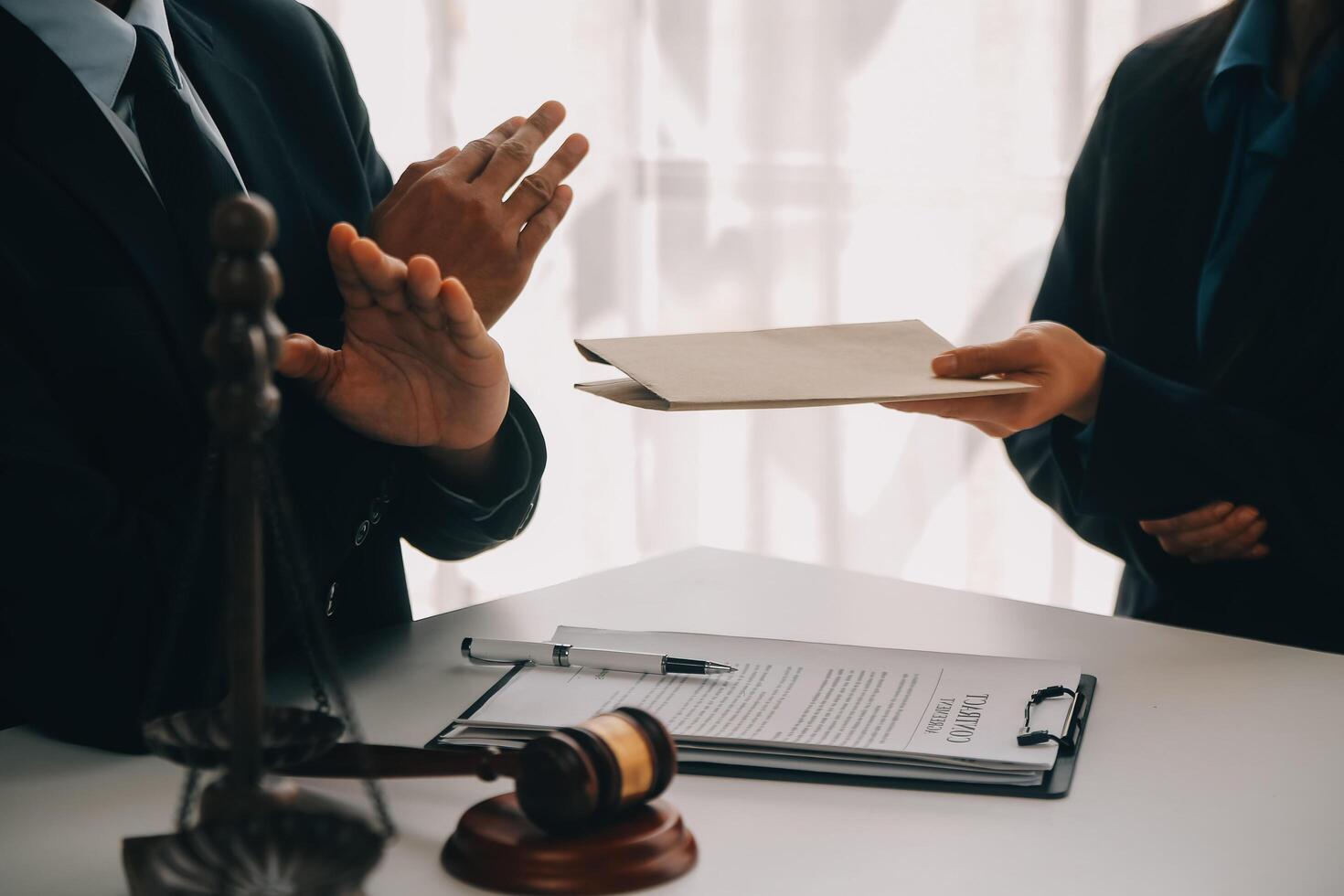 Justice and Law concept. Legal counsel presents to the client a signed contract with gavel and legal law or legal having team meeting at law firm in background photo