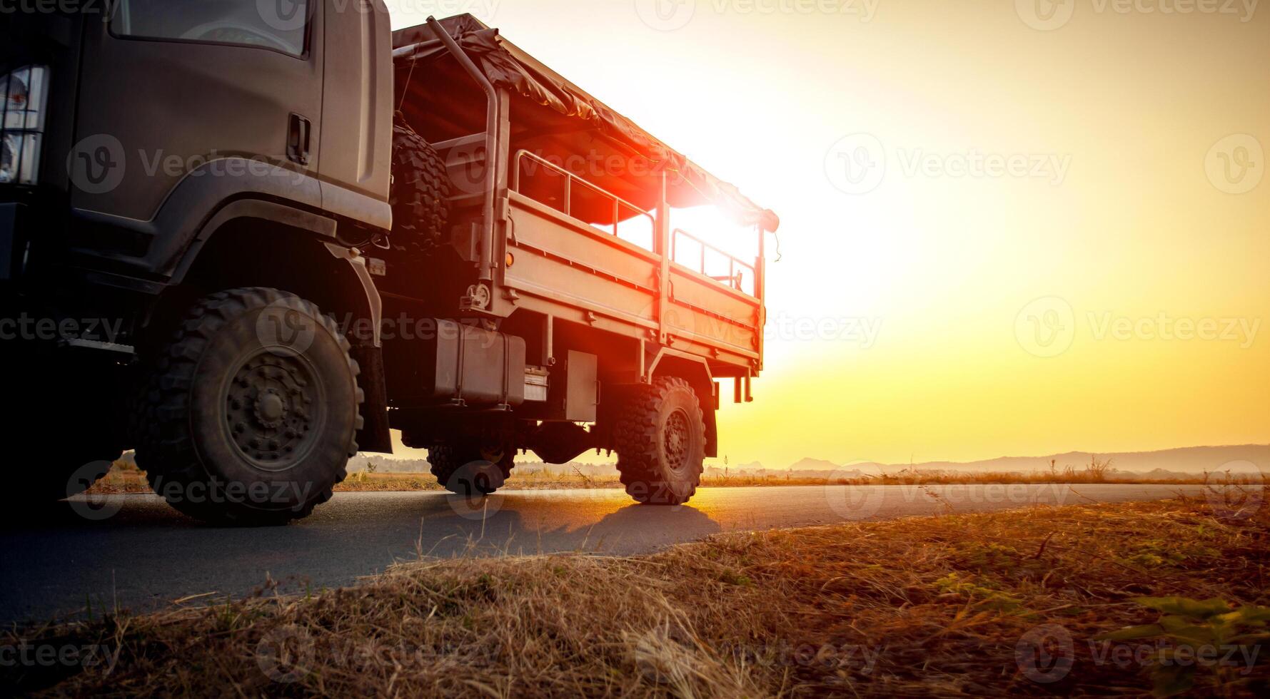 military truck running on asphalt highway against beautiful sunset sky photo