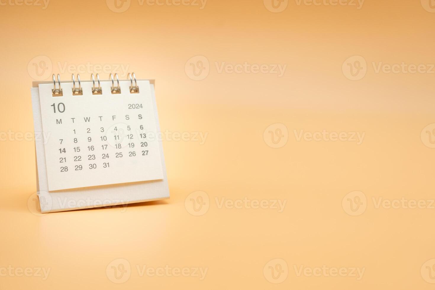 Simple desk calendar for October 2024 isolated on orange background. Calendar concept with copy space. photo