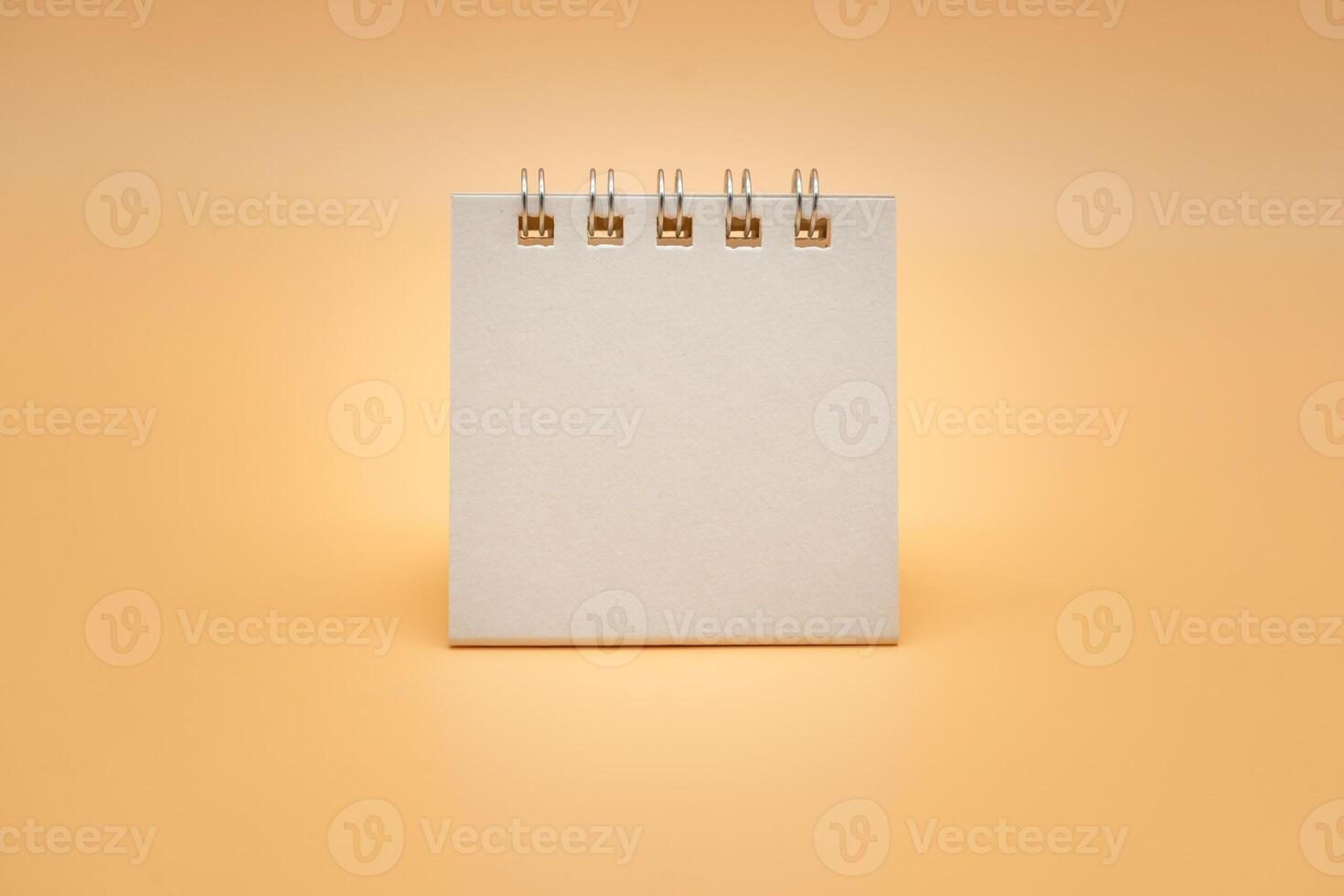 blanco calendario aislado en naranja antecedentes. blanco papel escritorio espiral calendario. cerca arriba de un blanco reciclar papel modelo. foto