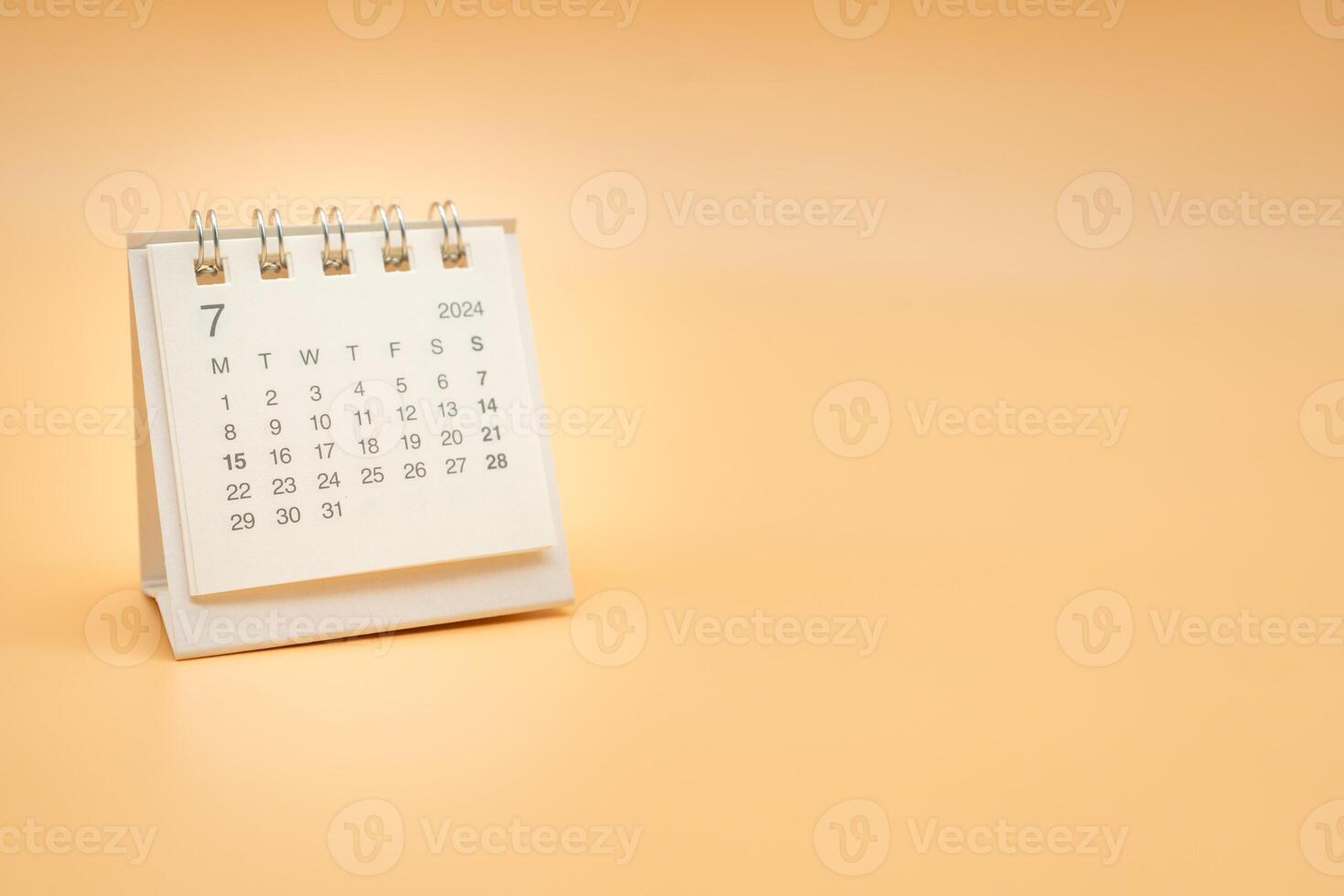 Simple desk calendar for July 2024 isolated on orange background. Calendar concept with copy space. photo