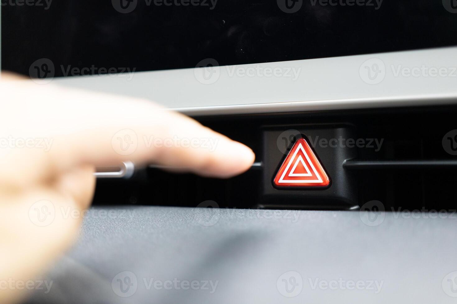 presses the emergency stop button in the car. Car emergency warning light button in front car console photo