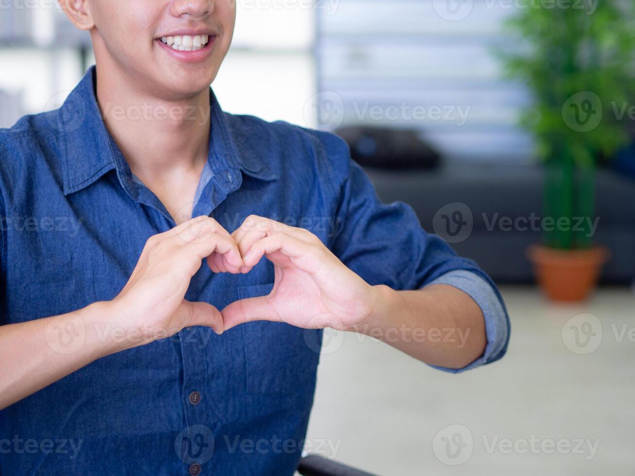 Close-up of a young man making a heart shape with fingers. Concept of couple and love. Valentine's day. Space for text photo