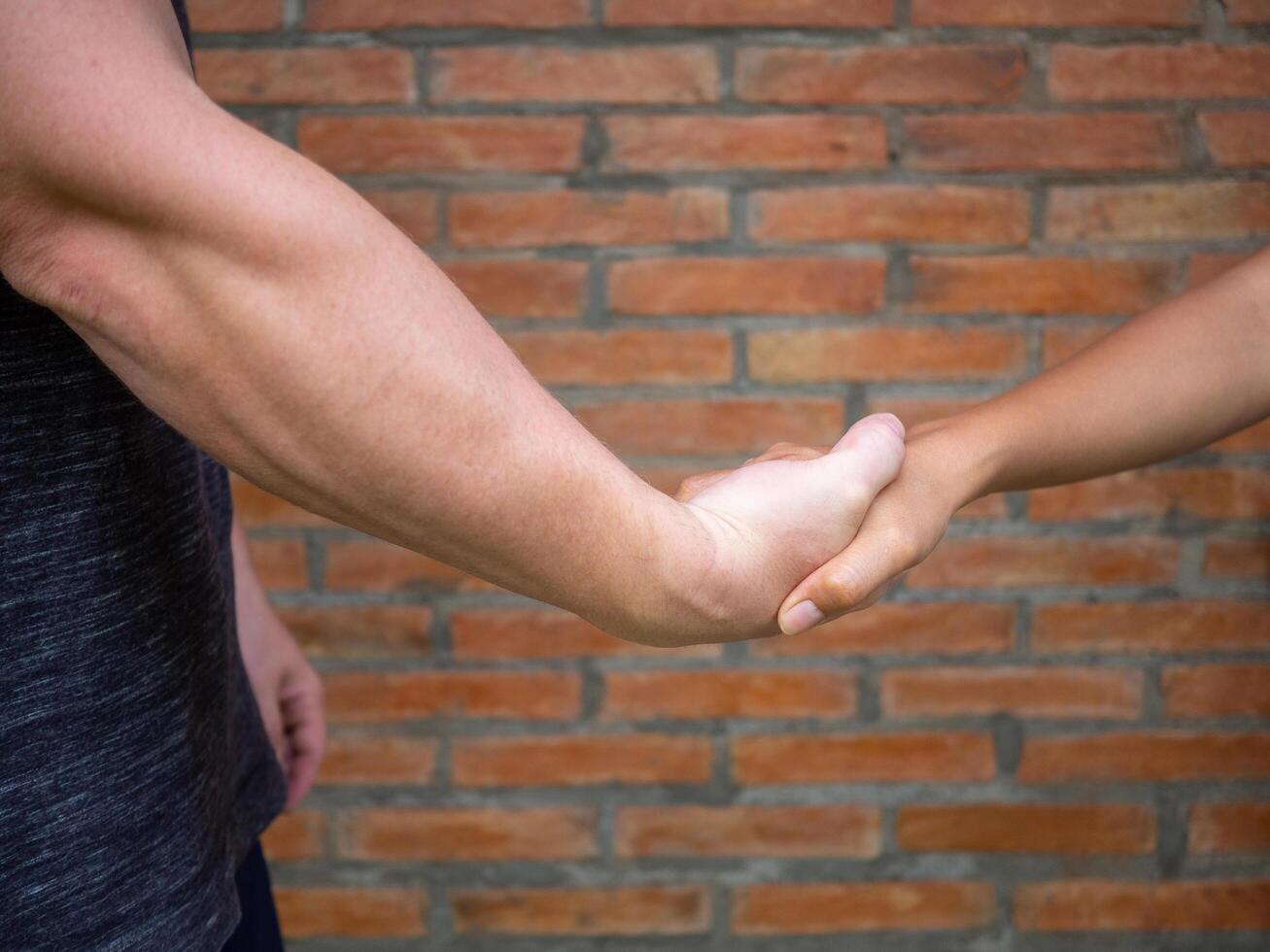 de cerca de sacudida manos Entre hombre y mujer con un ladrillo antecedentes. concepto de camaradería y trabajo en equipo foto