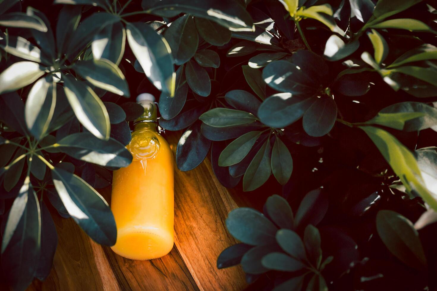 Top view fresh orange juice in a glass bottle lies on a wooden background. photo