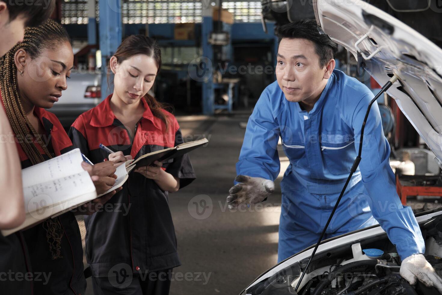 asiático masculino profesional automotor ingeniero supervisor describe coche motor mantenimiento y reparar trabajo con mecánico trabajador personal equipo en reparar Servicio cochera, especialista ocupaciones en auto industria. foto