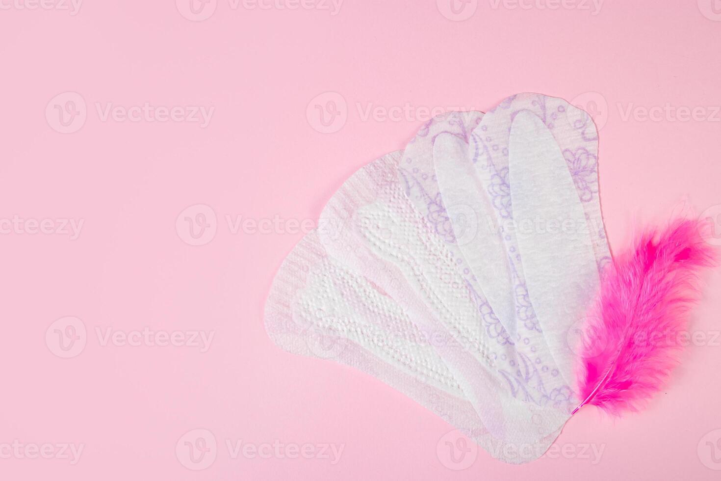 sanitario almohadillas y rosado pluma en de colores antecedentes. diario femenino higiene producto. foto