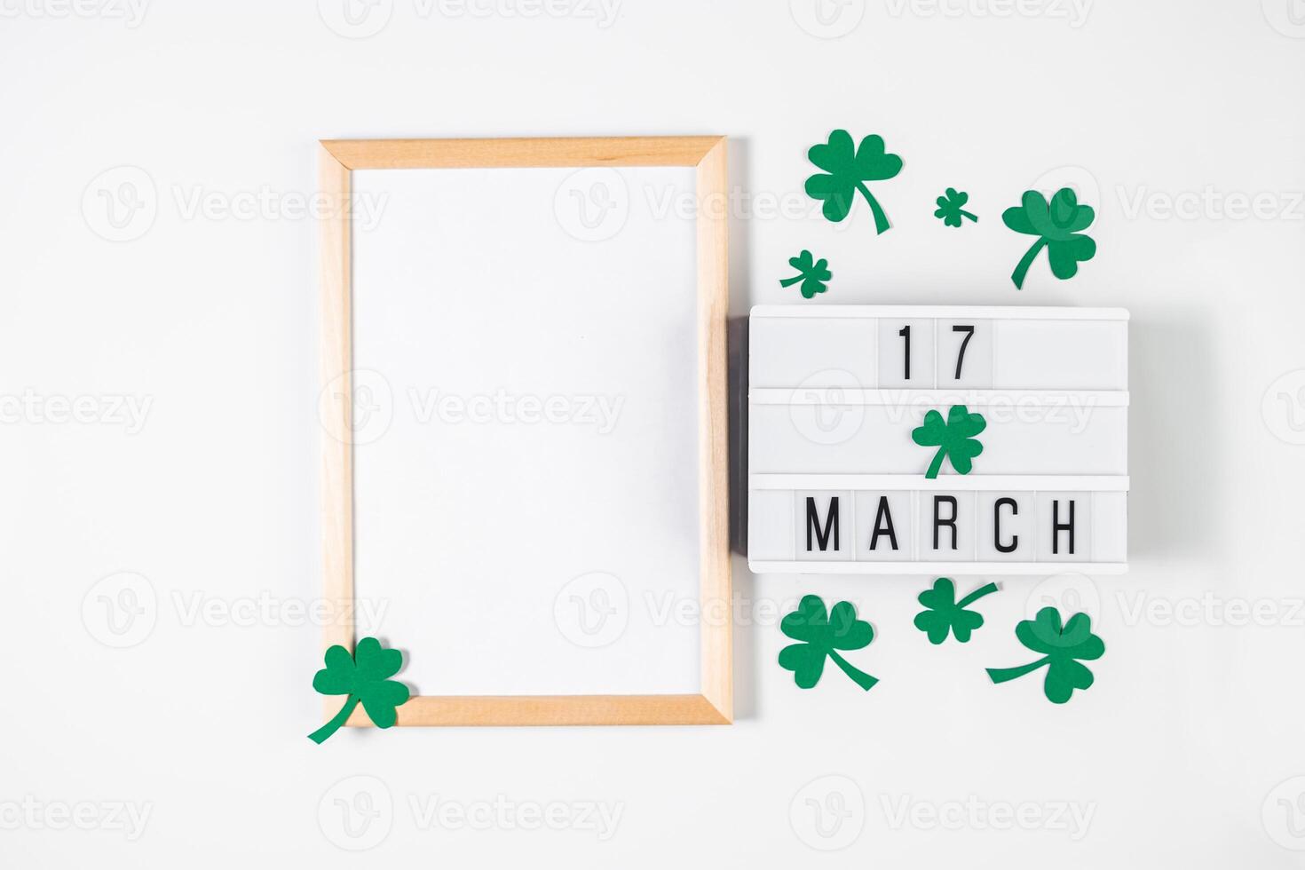 Minimalistic flatlay for St. Patrick's Day. Shamrock and frame on a white background. Happy Irish holiday, symbols of good luck. photo