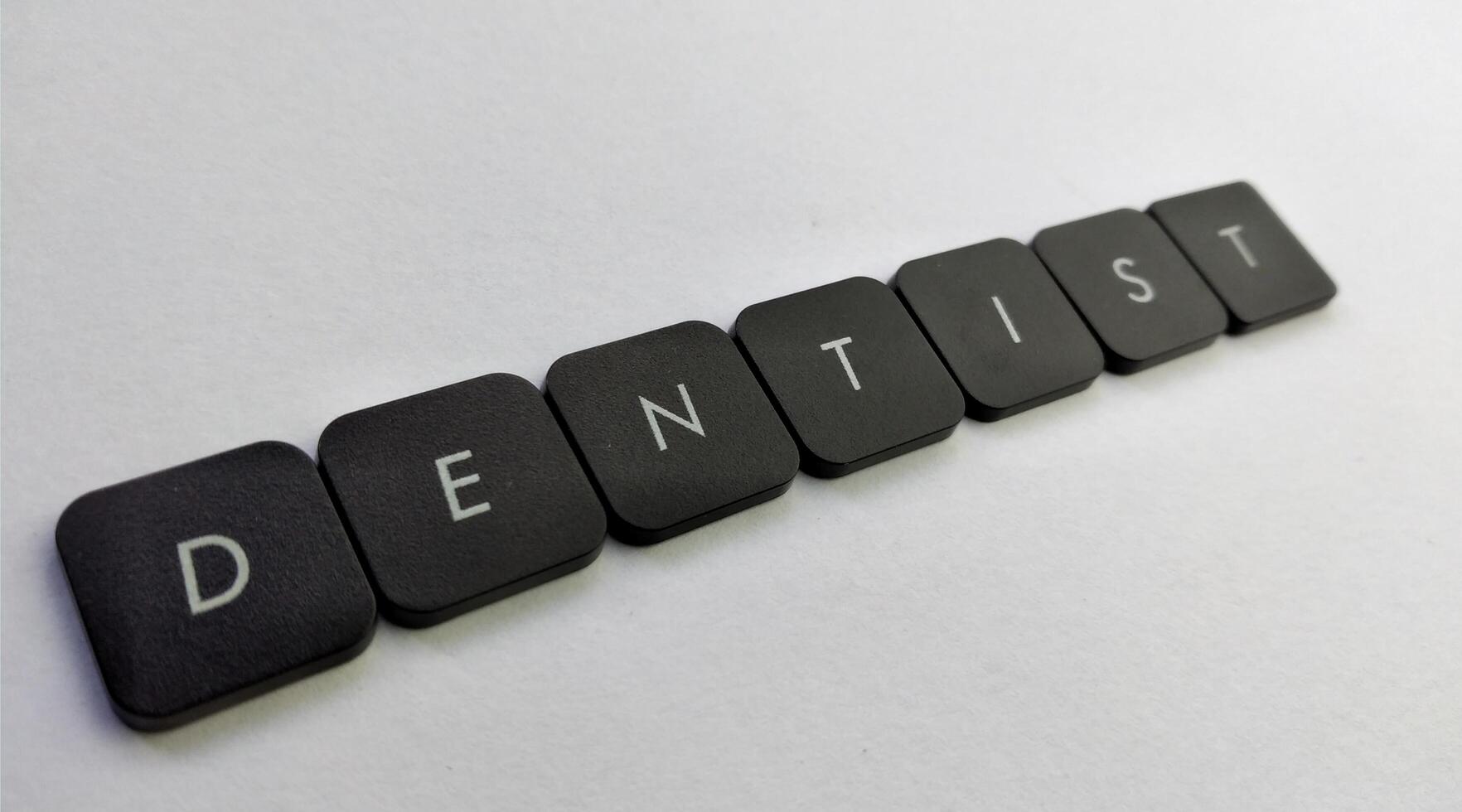 Word DENTIST spelled with black plastic letters on a white background photo