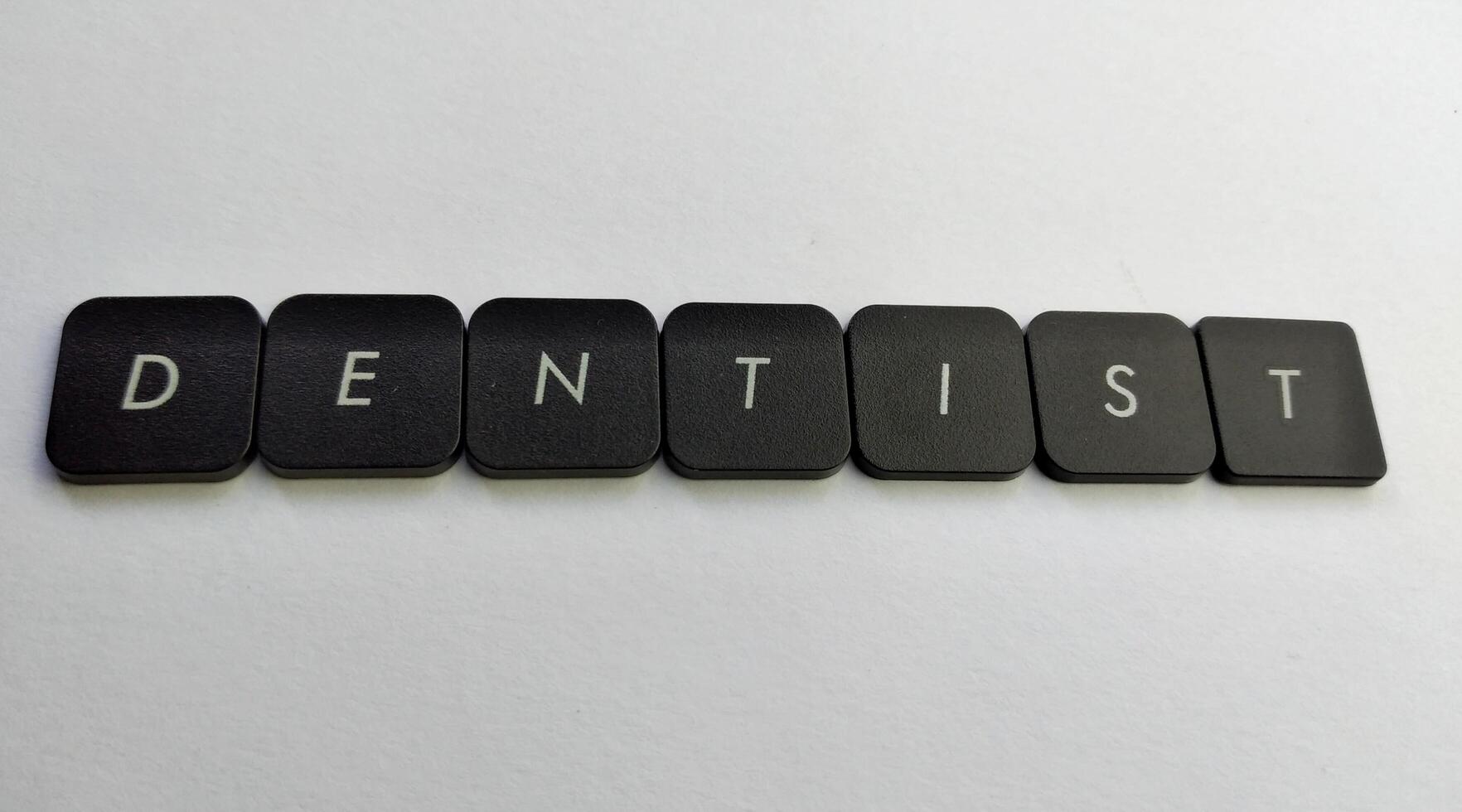 Word DENTIST spelled with black plastic letters on a white background photo