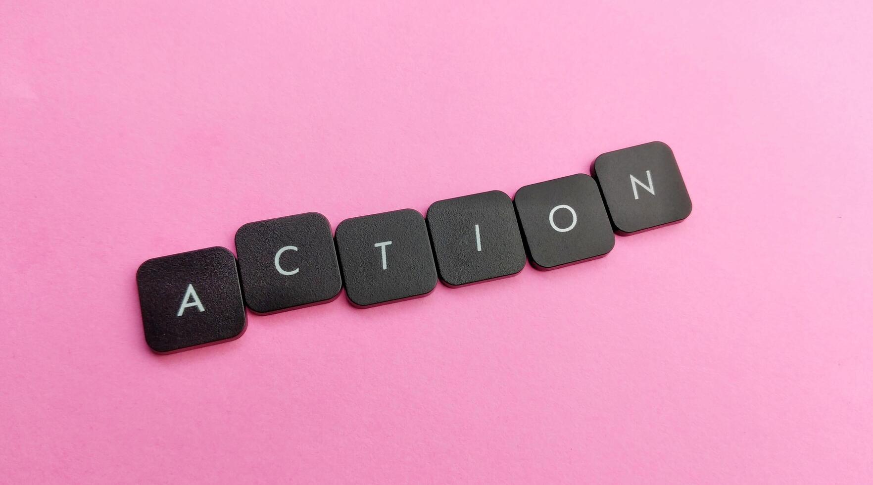 The word Action spelled out in black plastic buttons on a pink background photo