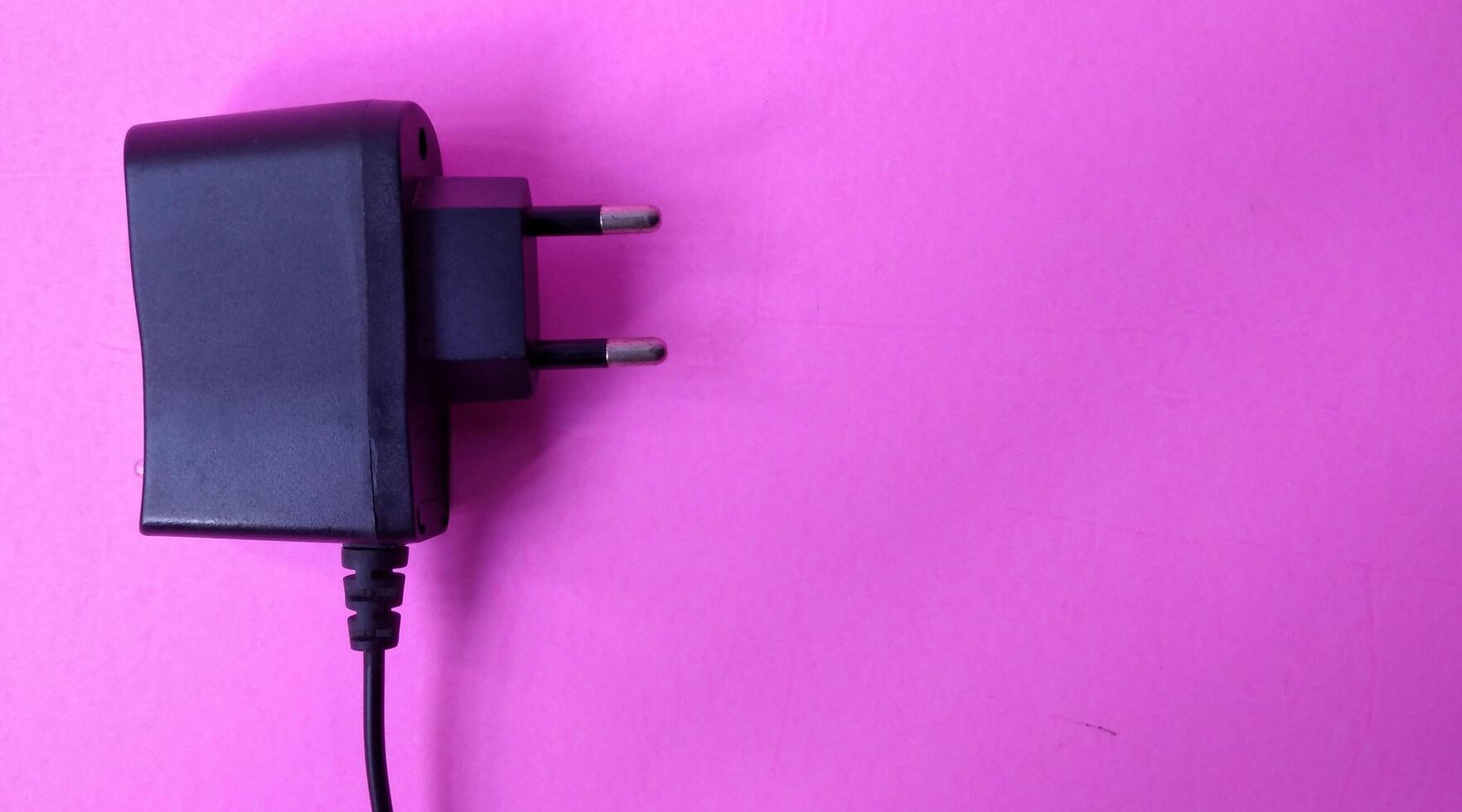 Black power plug on a pink background. Copy space for text. photo