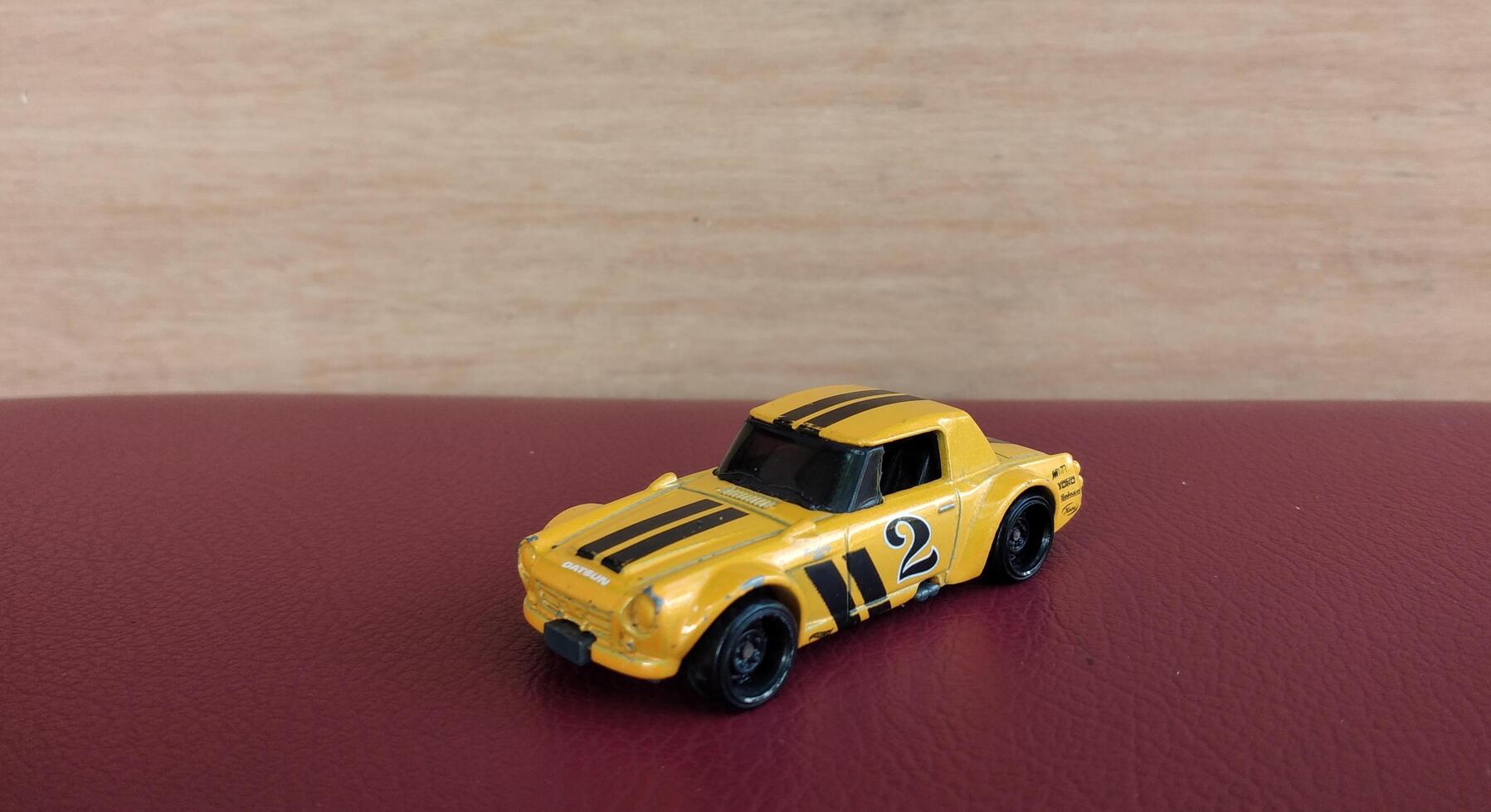 Miniature yellow car toy on red background with copy space for text photo