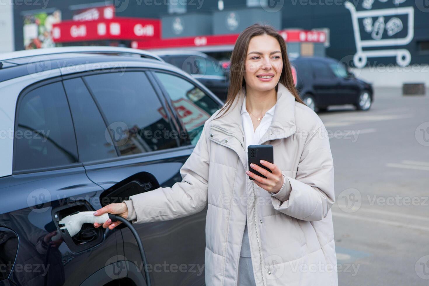 Young woman charging her electric car at a charging station in the city. Eco fuel concept. The concept of environmentally friendly transport. Recharging battery from charging station. photo