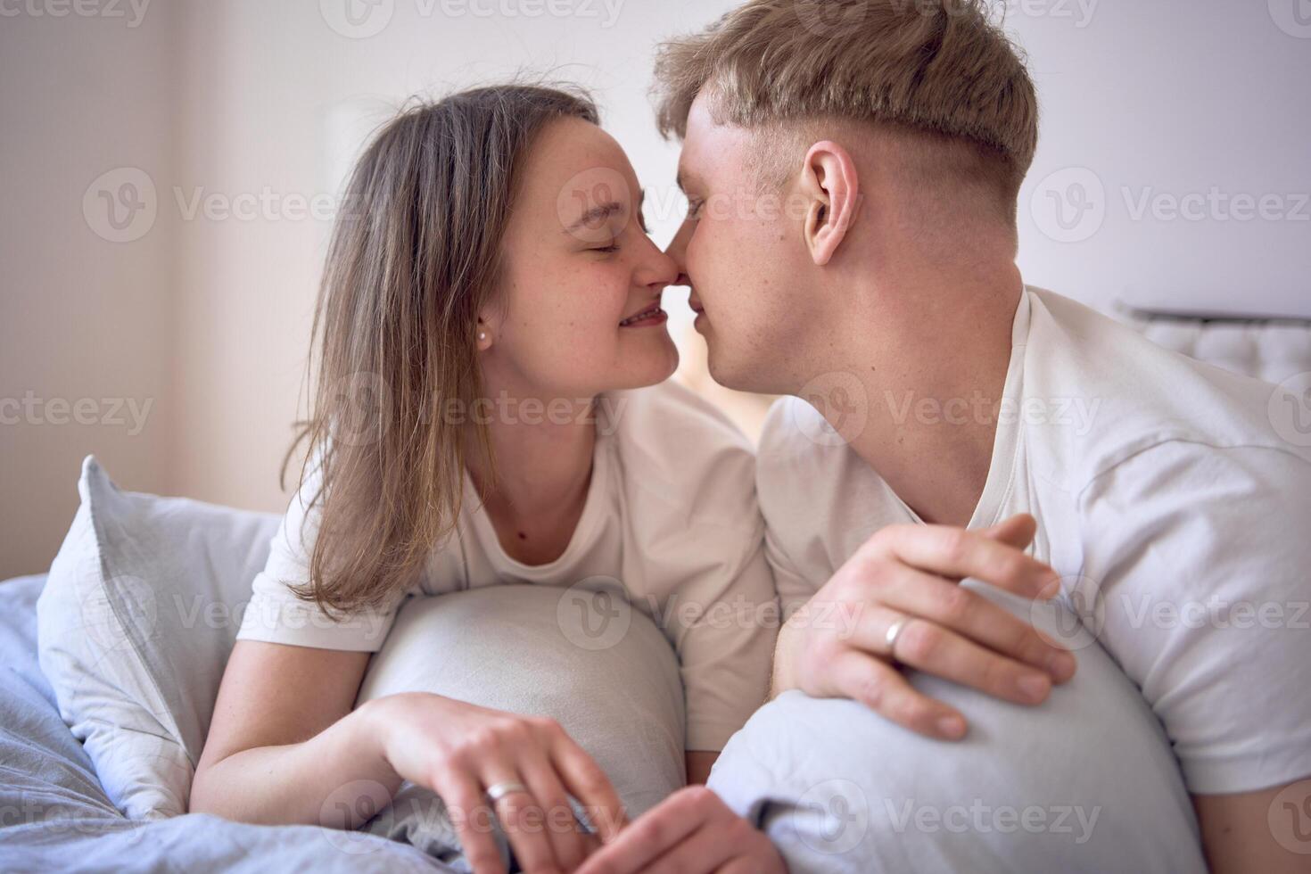 a young beautiful couple hugging and kissing in bed, wellness at home photo