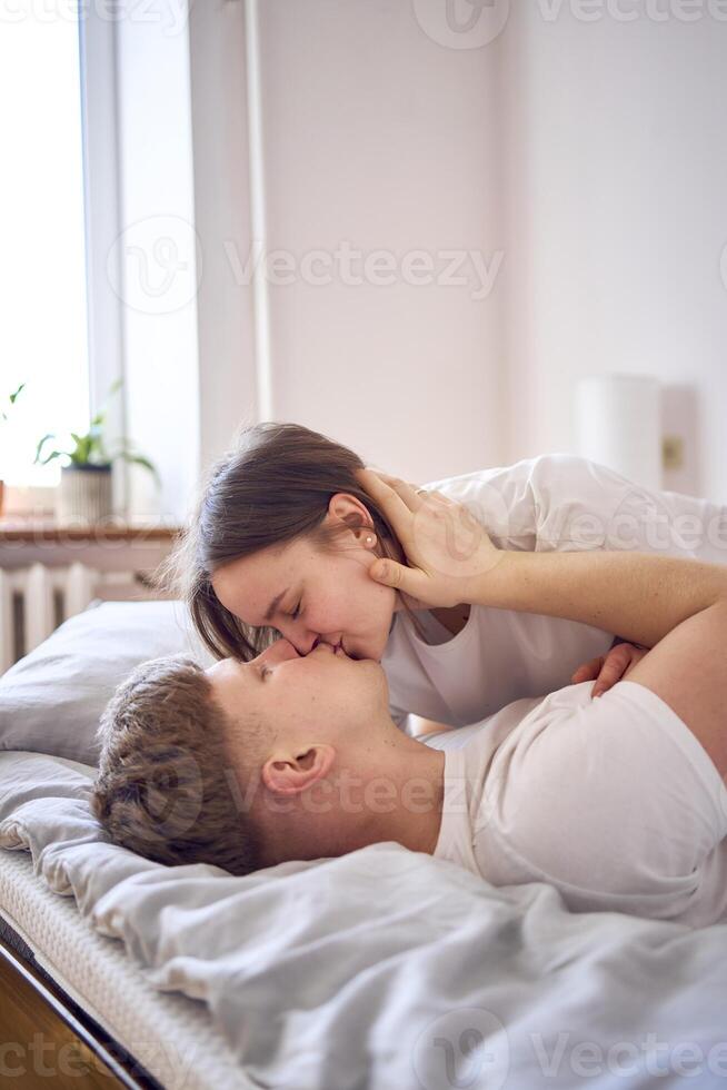 a young beautiful couple playing and wrestling on the bed, minimalism photo
