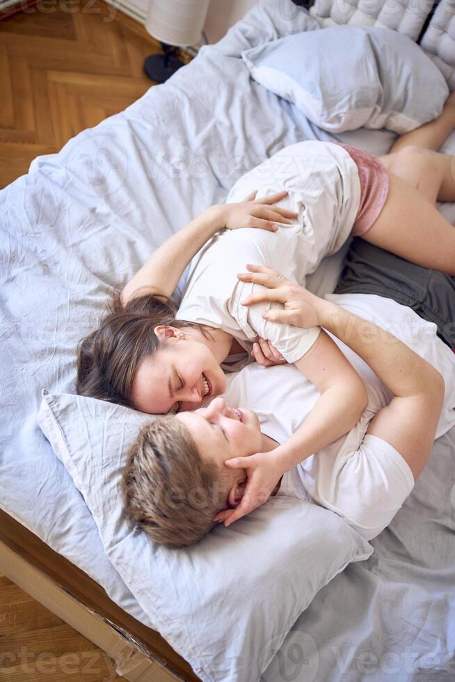 a young couple is lying on the bed, the girl is on the boy's shoulder, tender hugs photo