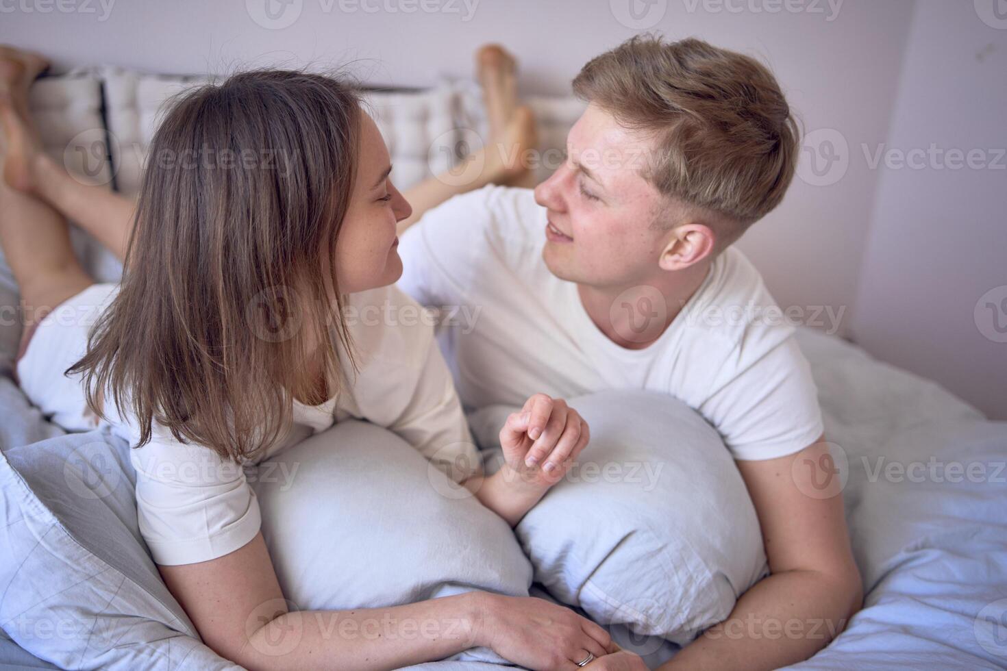a young beautiful couple hugging and kissing in bed, wellness at home photo