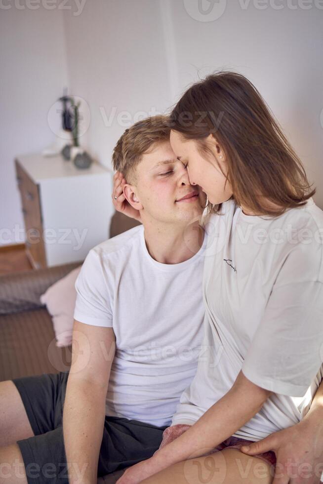 a young couple in home clothes gently hug in the living room, minimalism photo