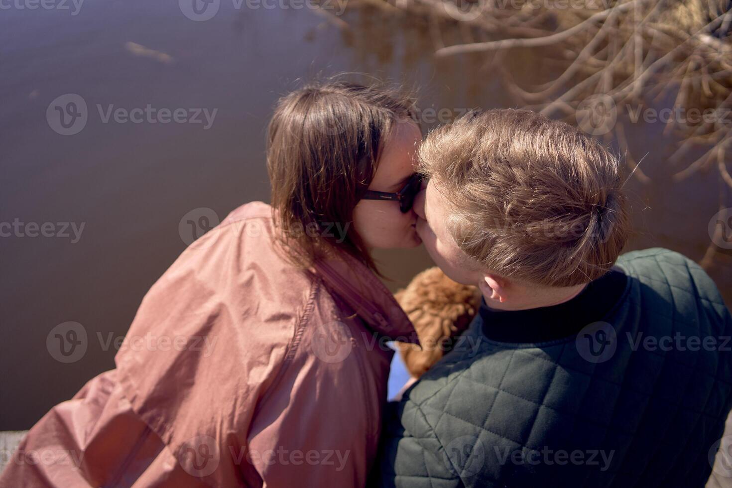 a young couple with a dog kissing on the pier photo