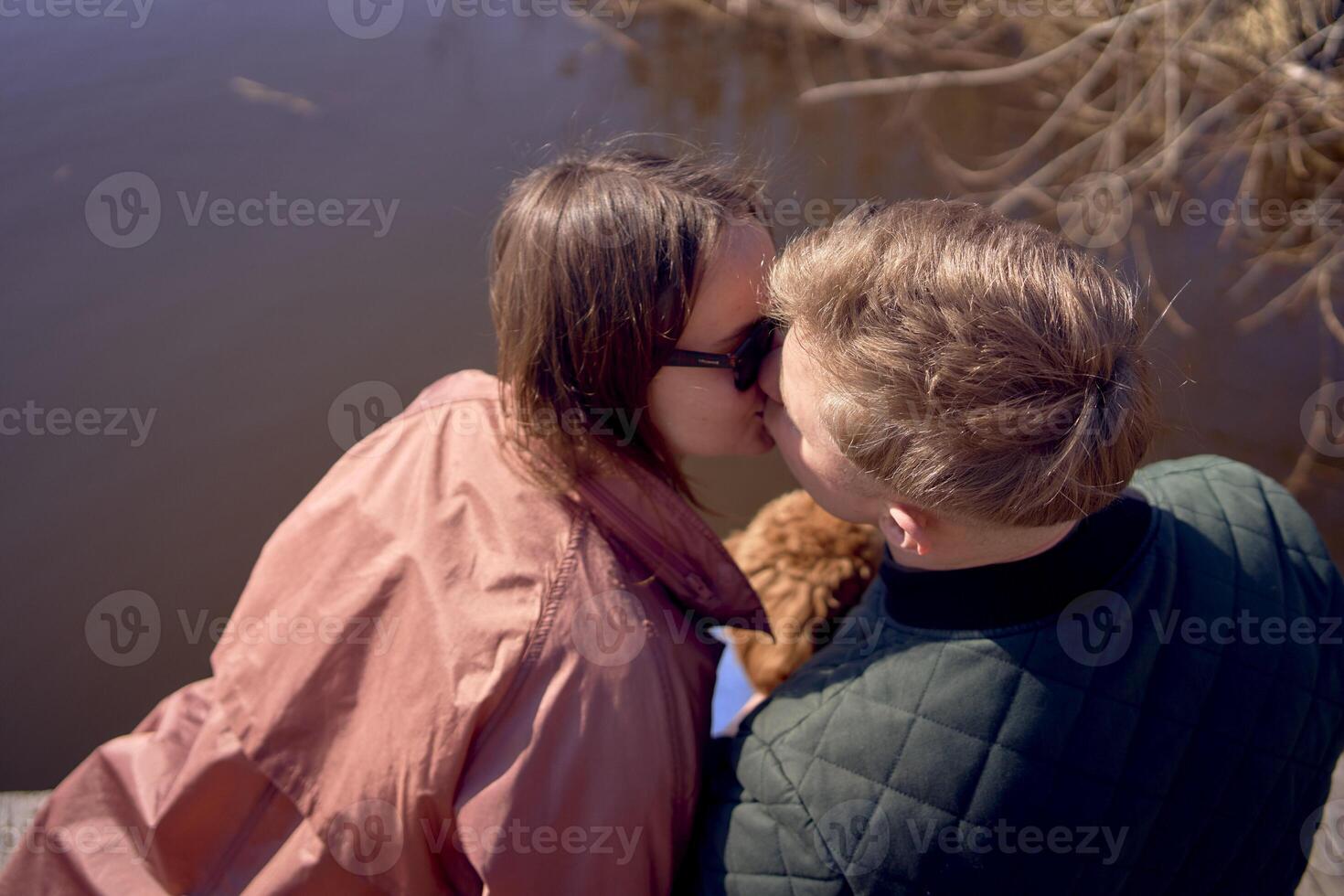 un joven Pareja con un perro besos en el muelle foto