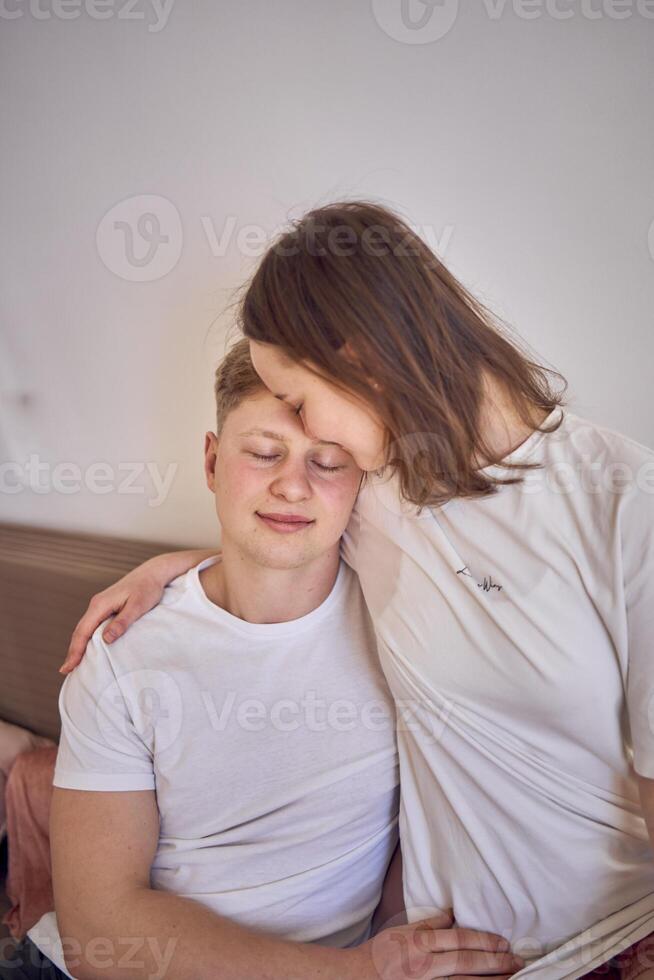 a young couple in home clothes gently hug in the living room, minimalism photo