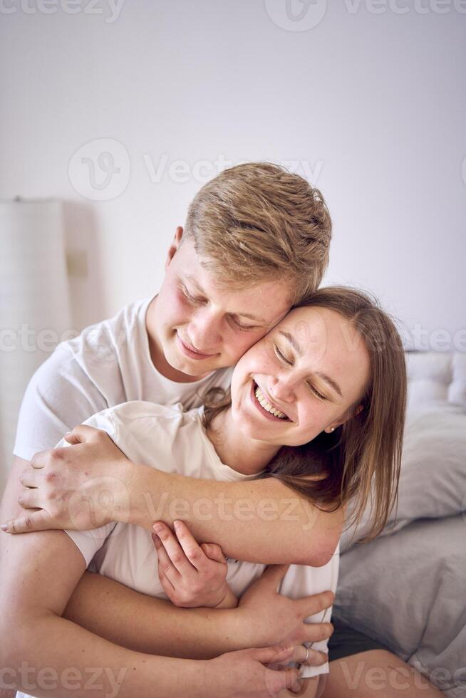 a man hugs his wife from behind, face to face photo