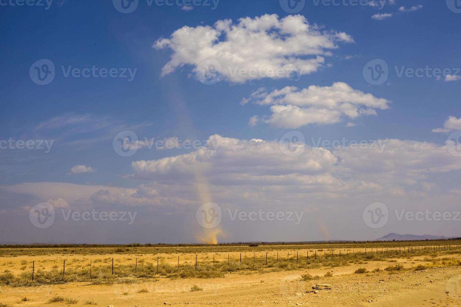 Whirlwind forms a dust pillar in the desert photo