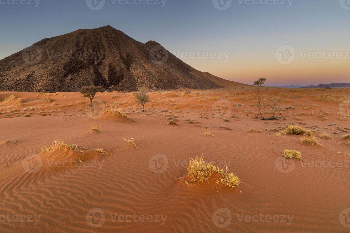 Red sand dune and black rock mountain photo