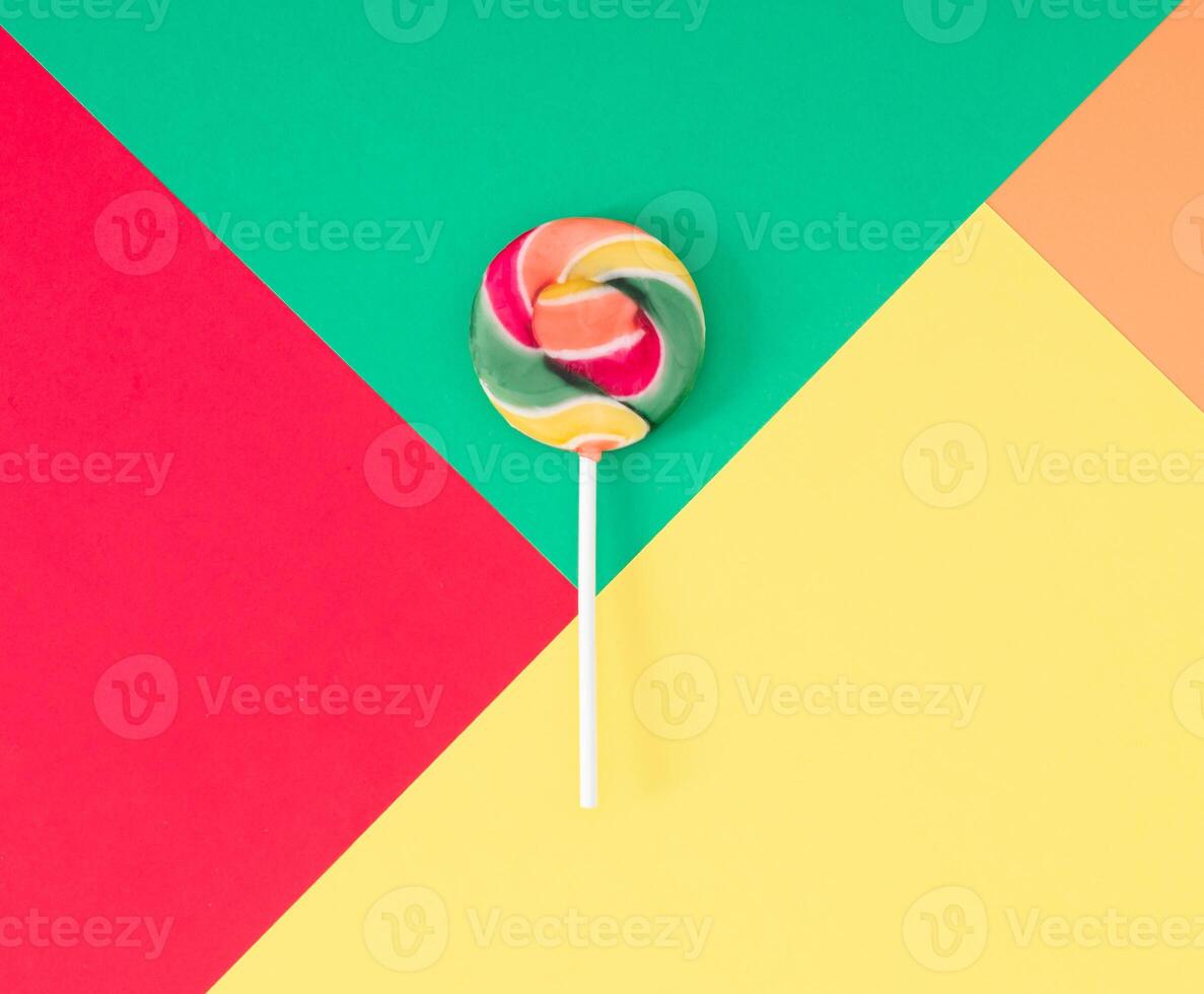 Colorful composition made with red, green, yellow and orange lollipop on red, green, yellow and orange abstract geometric background. Minimal concept. Trendy sweet food idea. Flat lay. photo