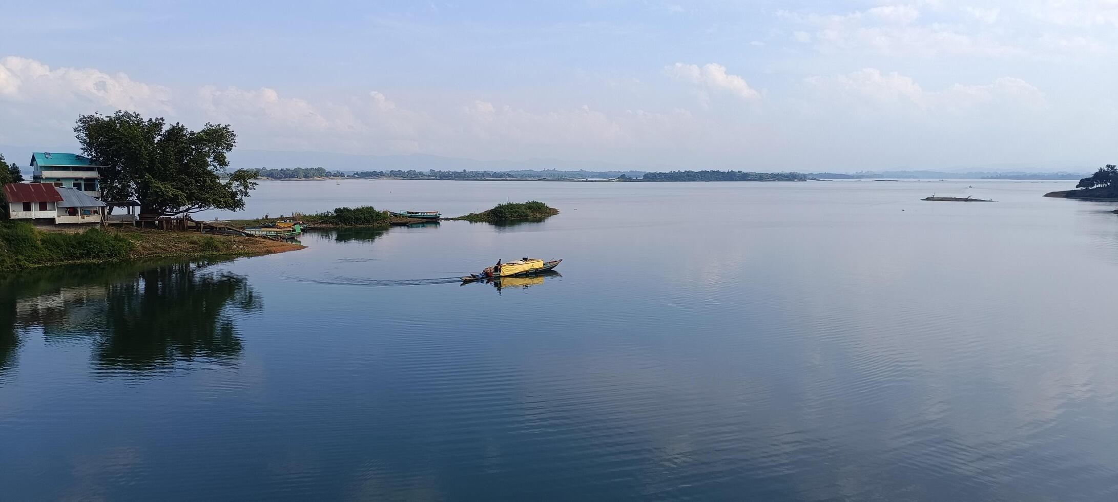 un barco es flotante en un lago cerca un pequeño pueblo foto