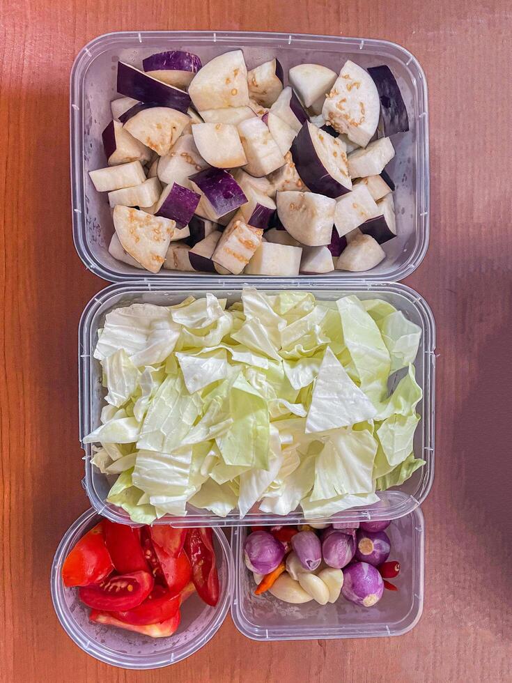top view of fresh cut vegetables in a container containing cabbage, eggplant onions and tomatoes photo