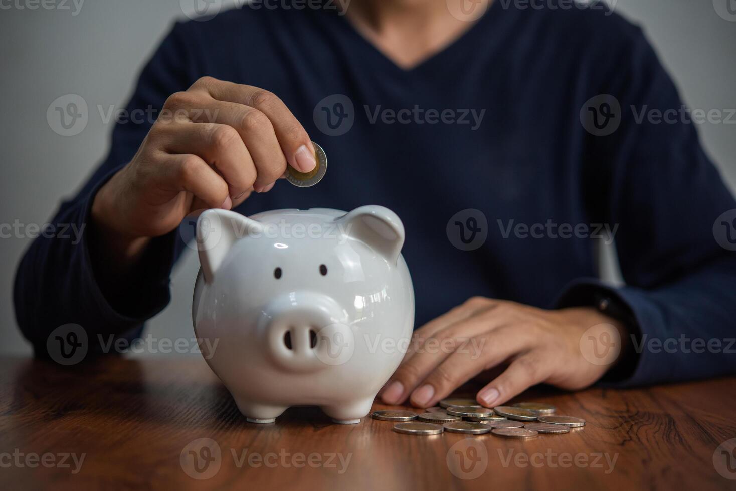 dinero ahorro concepto hombre sostiene monedas y gotas dentro un cerdito banco. negocio finanzas, bancario y inversión impuesto contabilidad foto