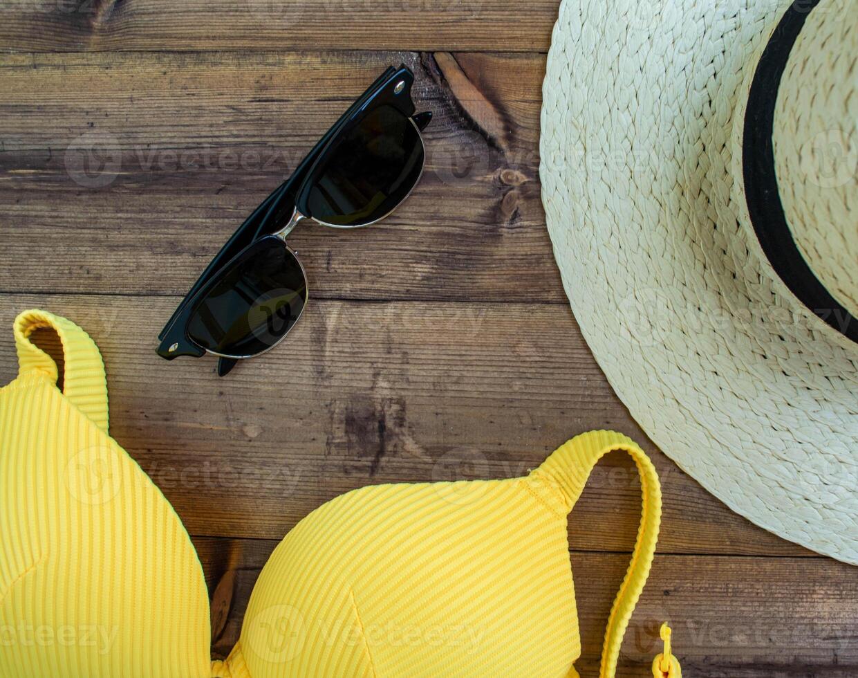 Summer vacation, flatlay. Hat, swimsuit and sunglasses on a wooden background. photo