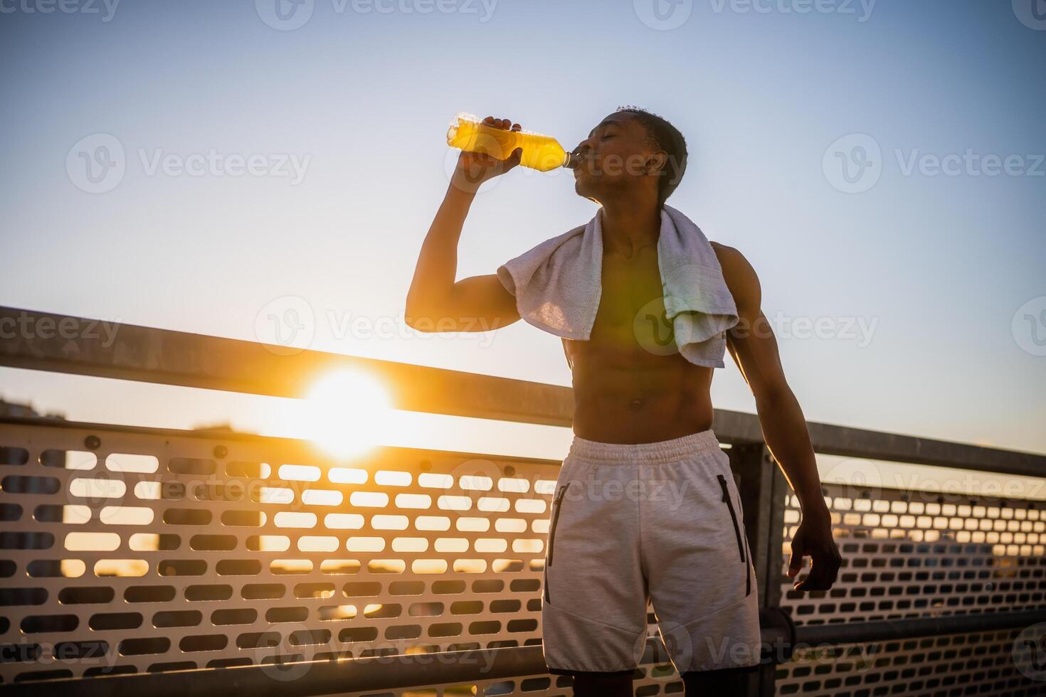 Portrait of young african-american man who is drinking water and relaxing after jogging. photo