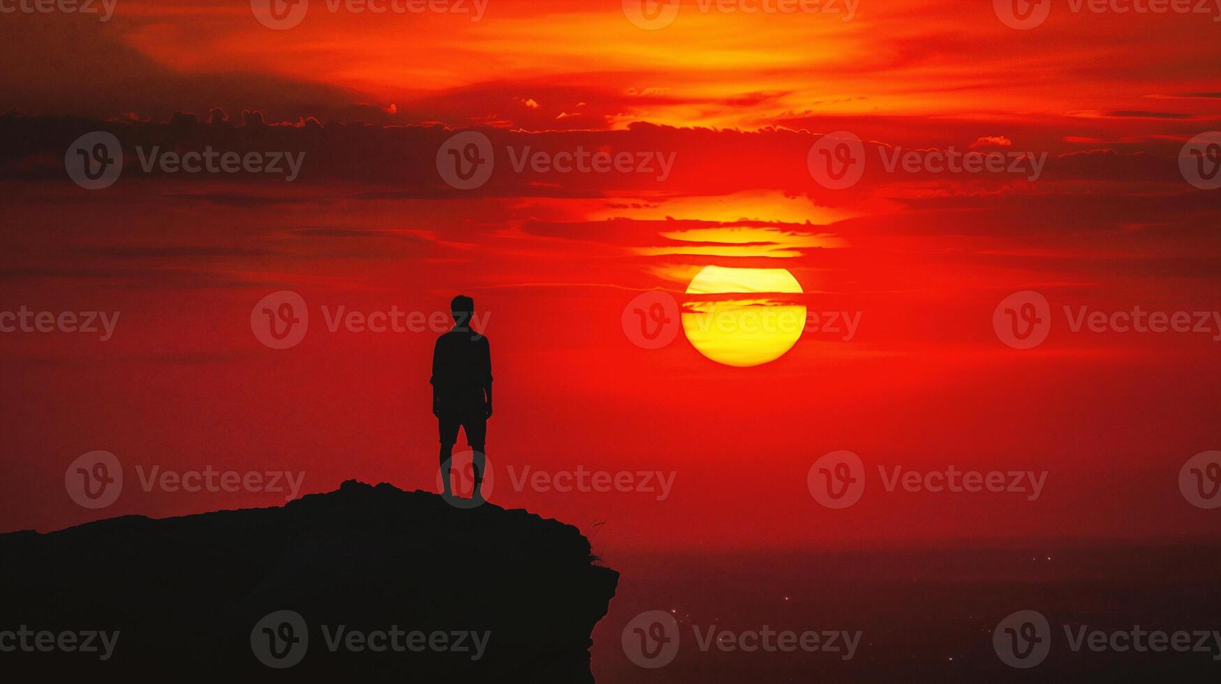 AI generated Silhouette of a man standing on top of a mountain and watching the sunset photo