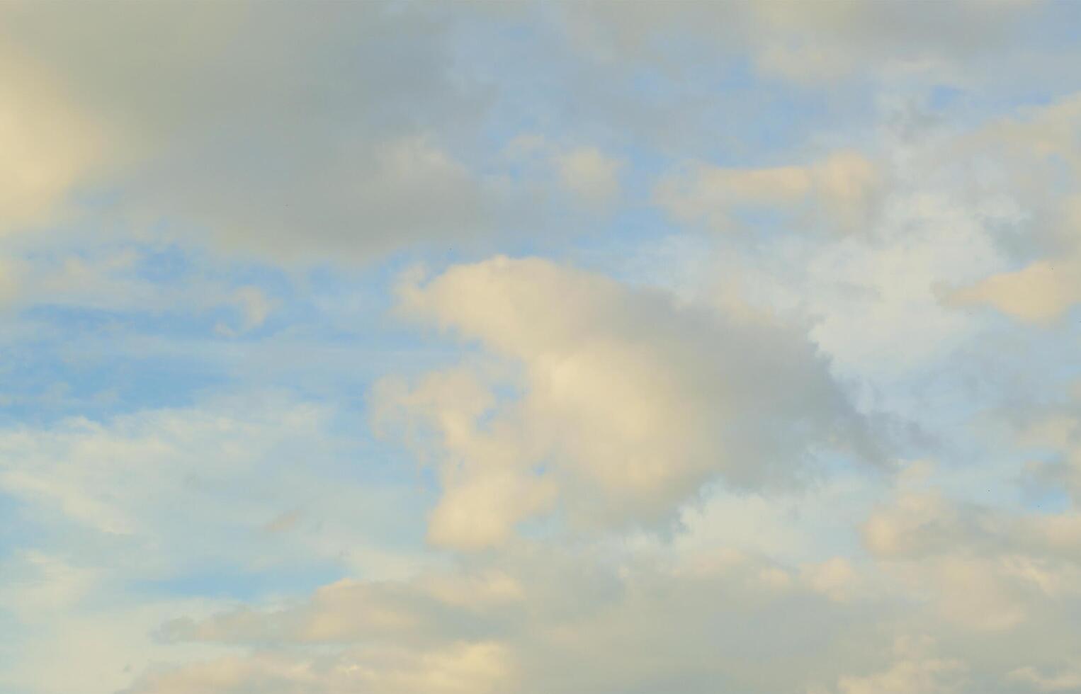 A blue cloudy sky with many small clouds blocking the sun photo