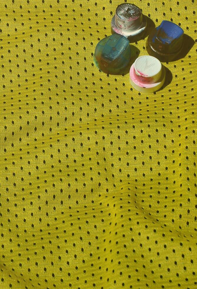 Several caps for used aerosol paint sprayers lie on the sports shirt of a basketball player made of polyester fabric. The concept of youth street art, active sports and eventful lifestyle photo