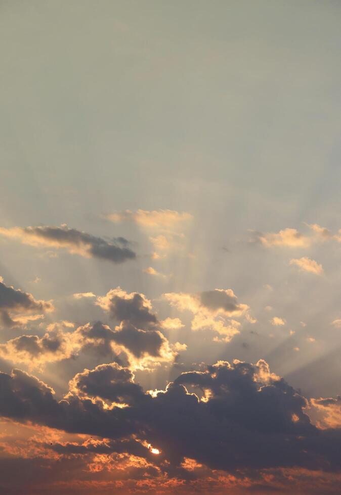 Beautiful sunrise with warm orange sunlight and beams through blue sky photo