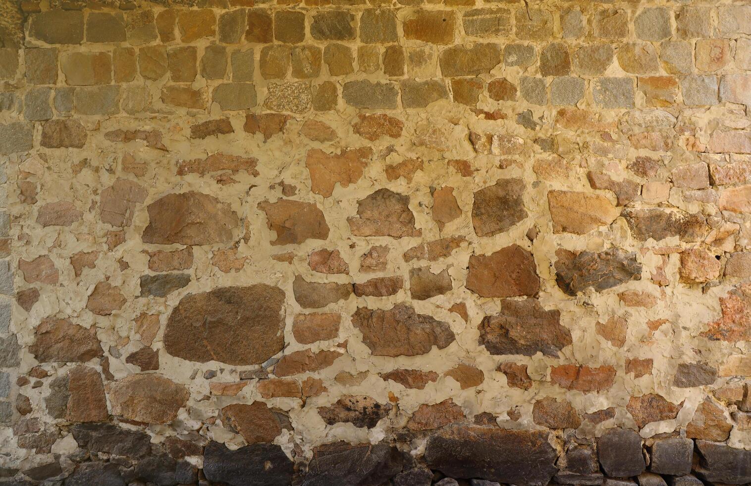 textura de una pared de piedra con muchas piedras marrones y grises grandes armadas con cemento. fondo de textura de pared de piedra de castillo antiguo para uso medieval. parte de un edificio de piedra foto